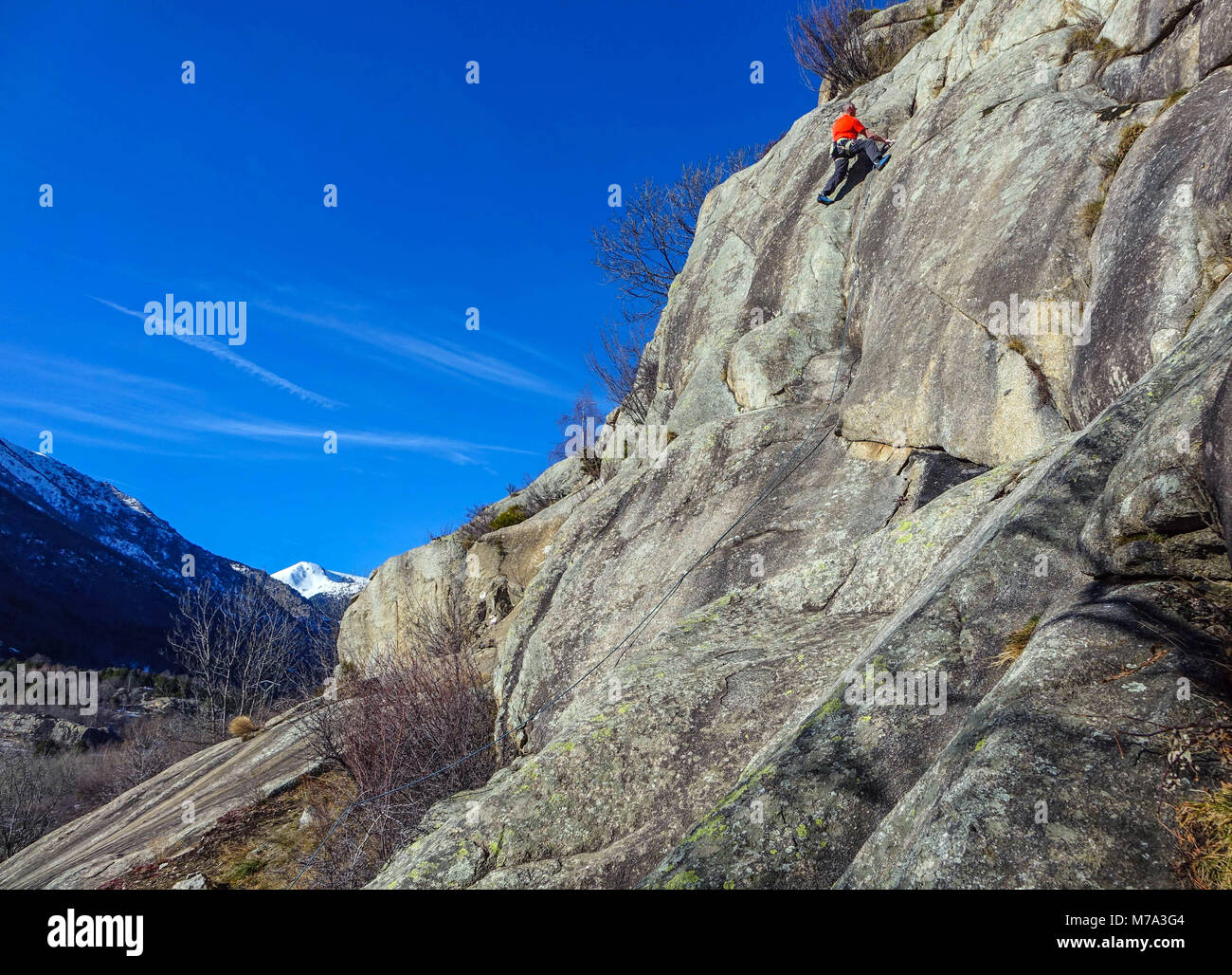 Male rock climber in red on granite cliff, Ariege, French Pyrenees