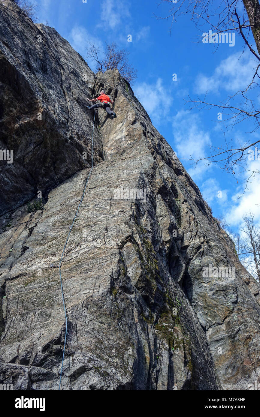 Male rock climber in red on granite cliff, Ariege, French Pyrenees