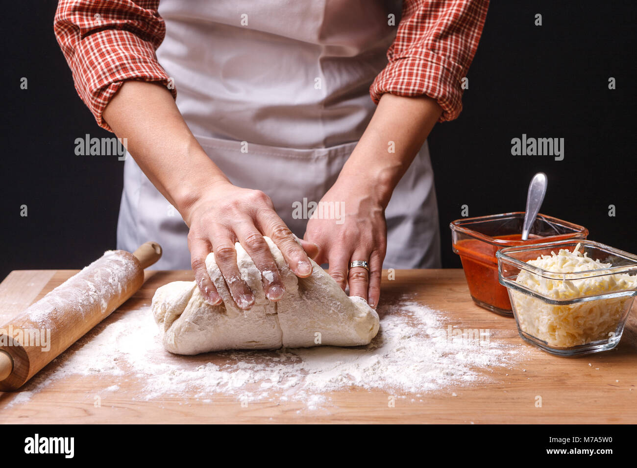 A woman is kneading pizza dough on a table Stock Photo - Alamy