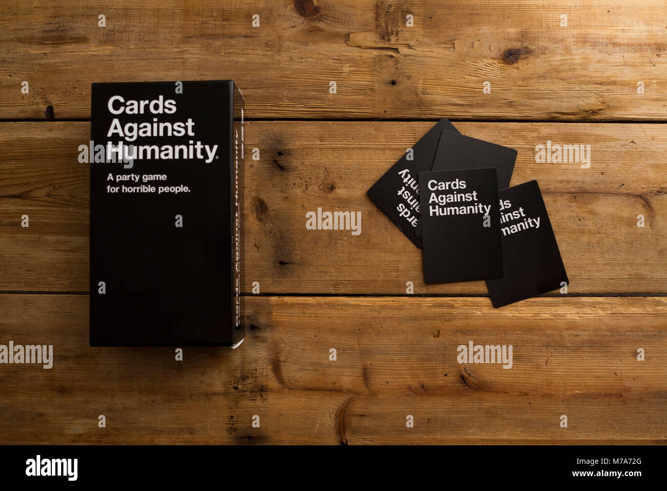 Cards Against Humanity, A party game for horrible people, displayed on a wooden table Stock Photo