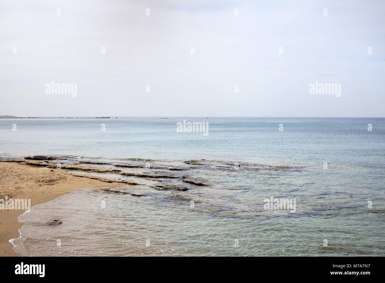 Sandy beach with rocks. Blue sky and calm sea background Stock Photo ...