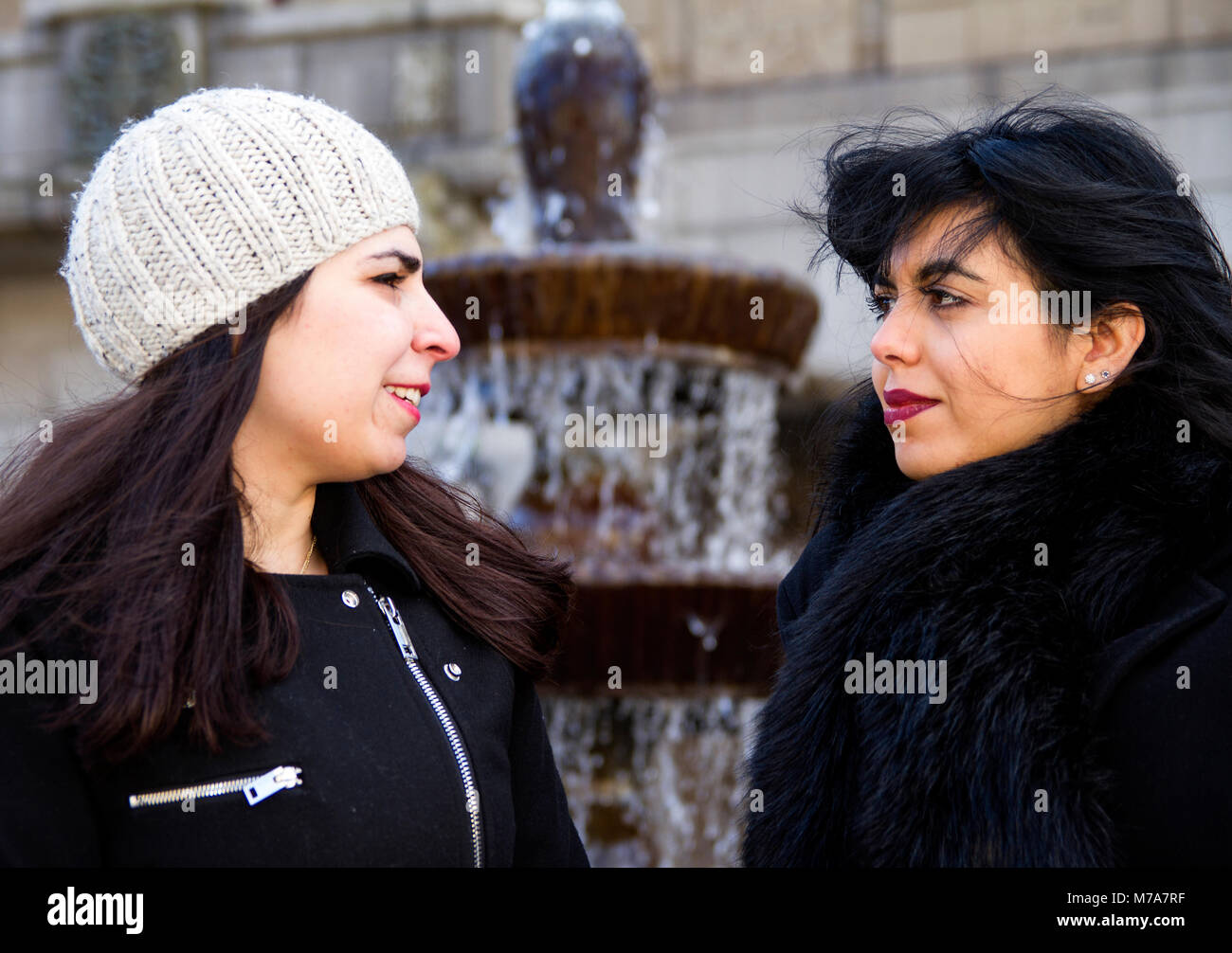 Two female students, Parisian-Algerian Faiza Faa (right) with her Iraqi friend Samar Munaf (left) sitting together at the City fountain in Dundee, UK Stock Photo