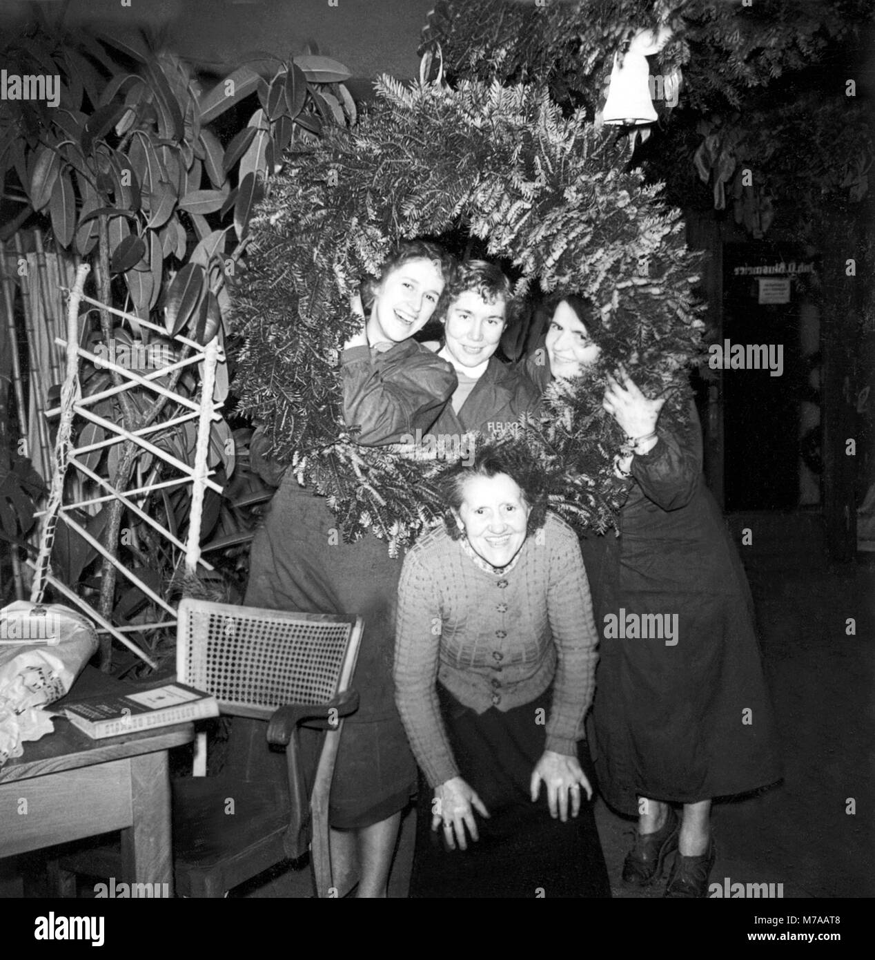 Saleswomen of a flower shop posing in front of a large Advent wreath, 1960s, Germany Stock Photo