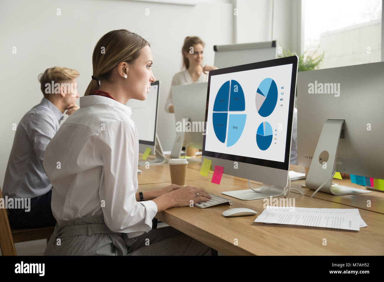 Focused woman working with statistics charts using computer in o Stock Photo