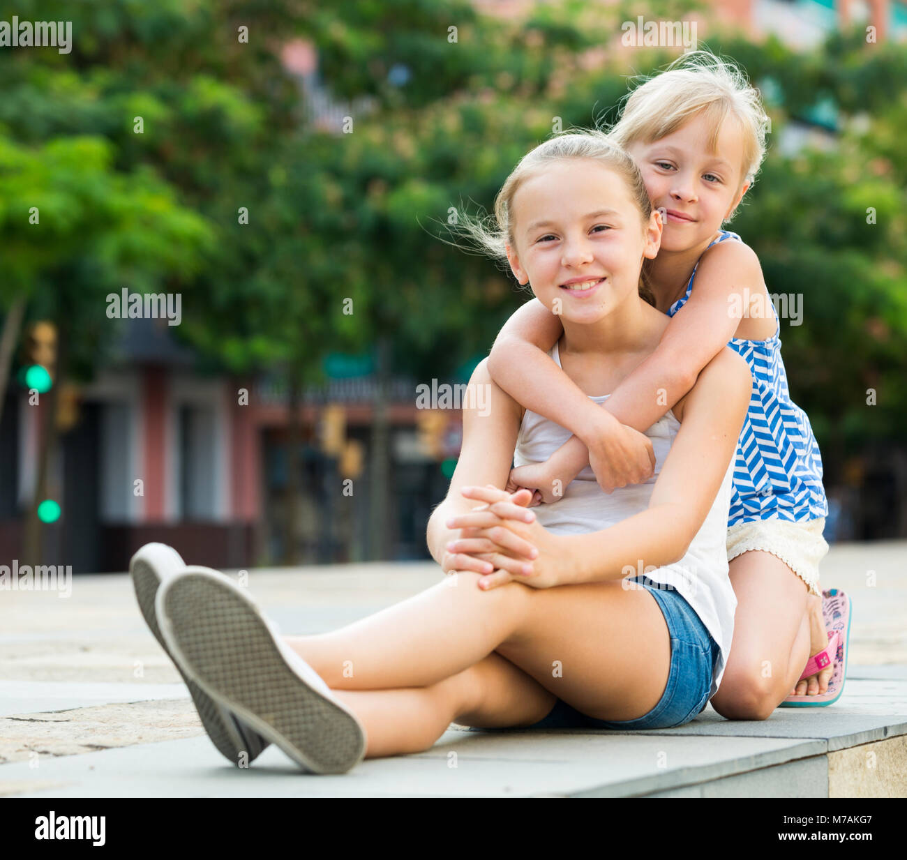Two smiling little girls embracing each other in summer park Stock ...