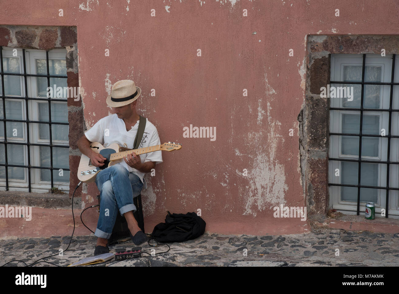Guitarist in front of wall of a house, Imerovigli, Santorini, Greek islands Stock Photo