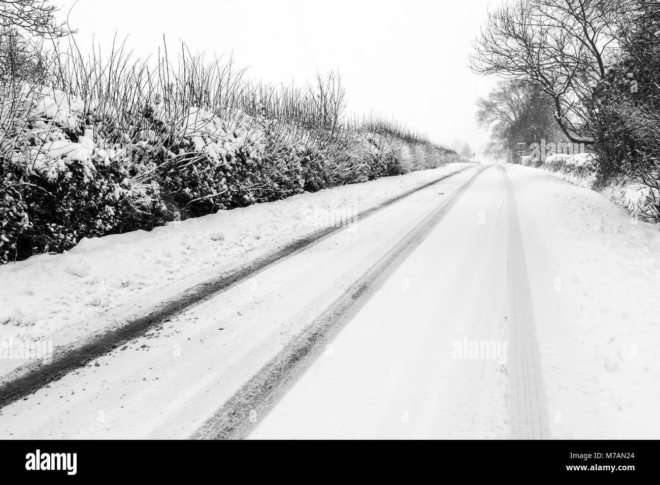 Tyre tracks lead into the distance in snowy conditions Stock Photo