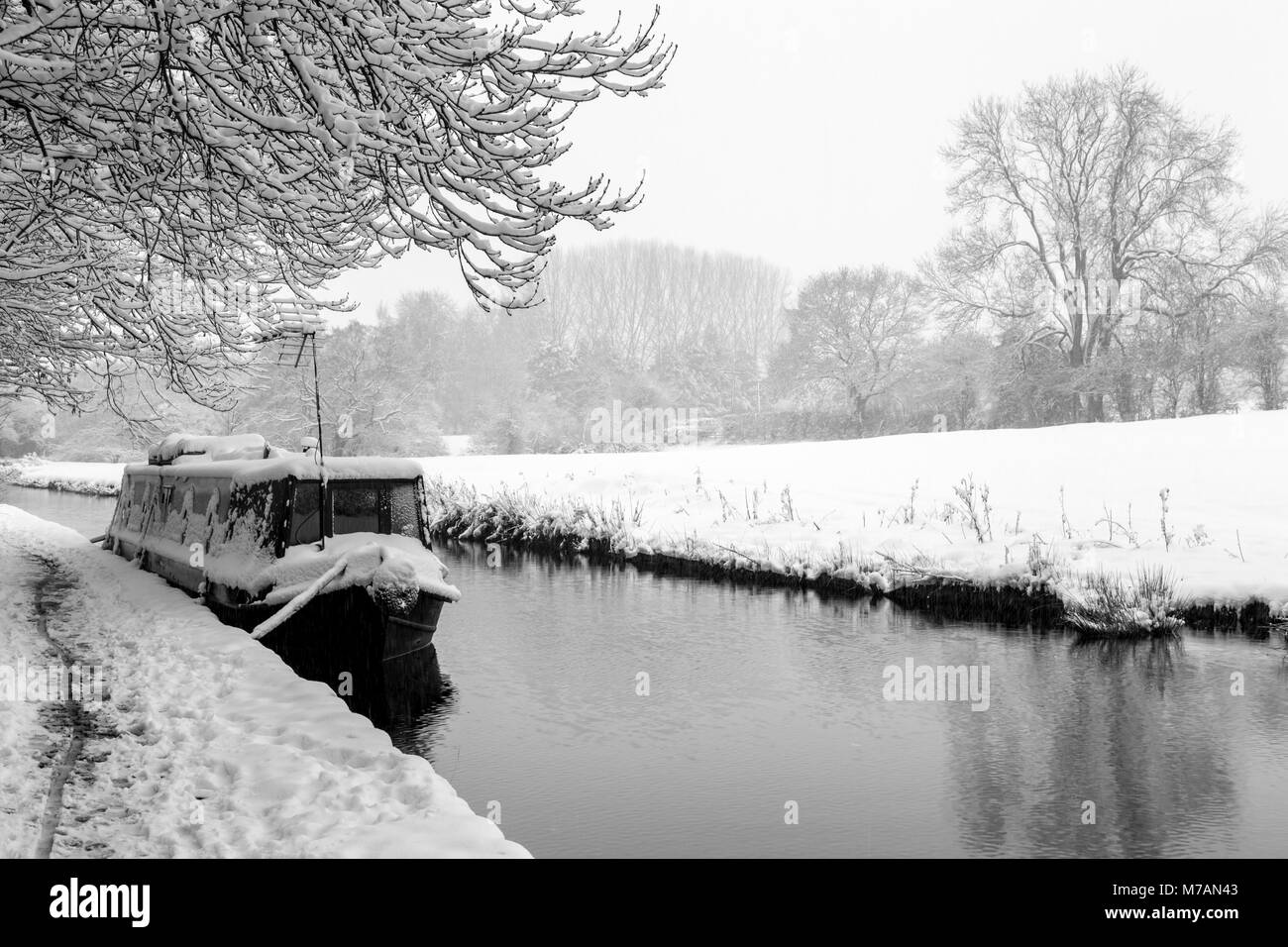 A Narrowboat covered in snow can be seen moored up on the Llangollen Canal Stock Photo