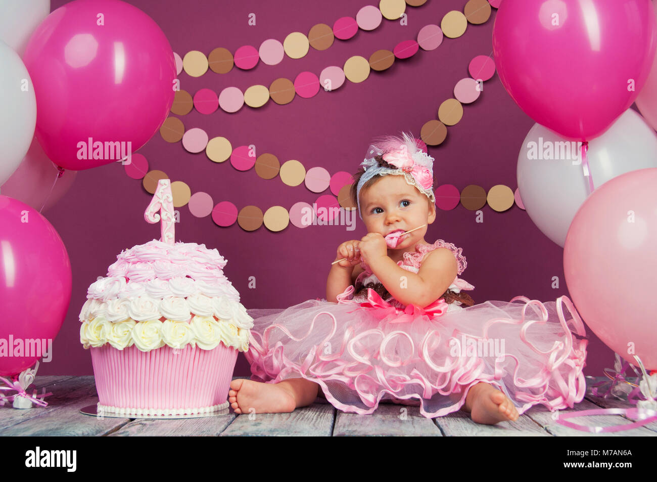 Portrait of a little cheerful birthday girl with the first cake. Eating the first cake. Smash