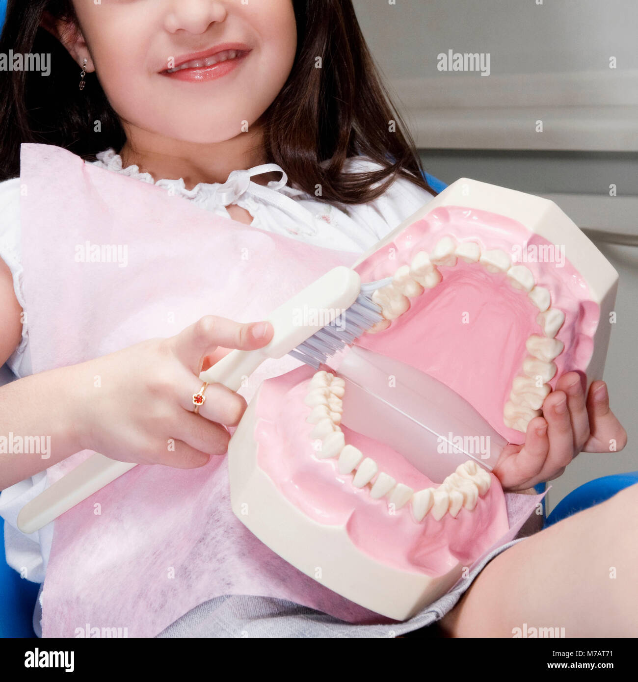 Girl learning how to brush teeth with the help of dentures in a dentist