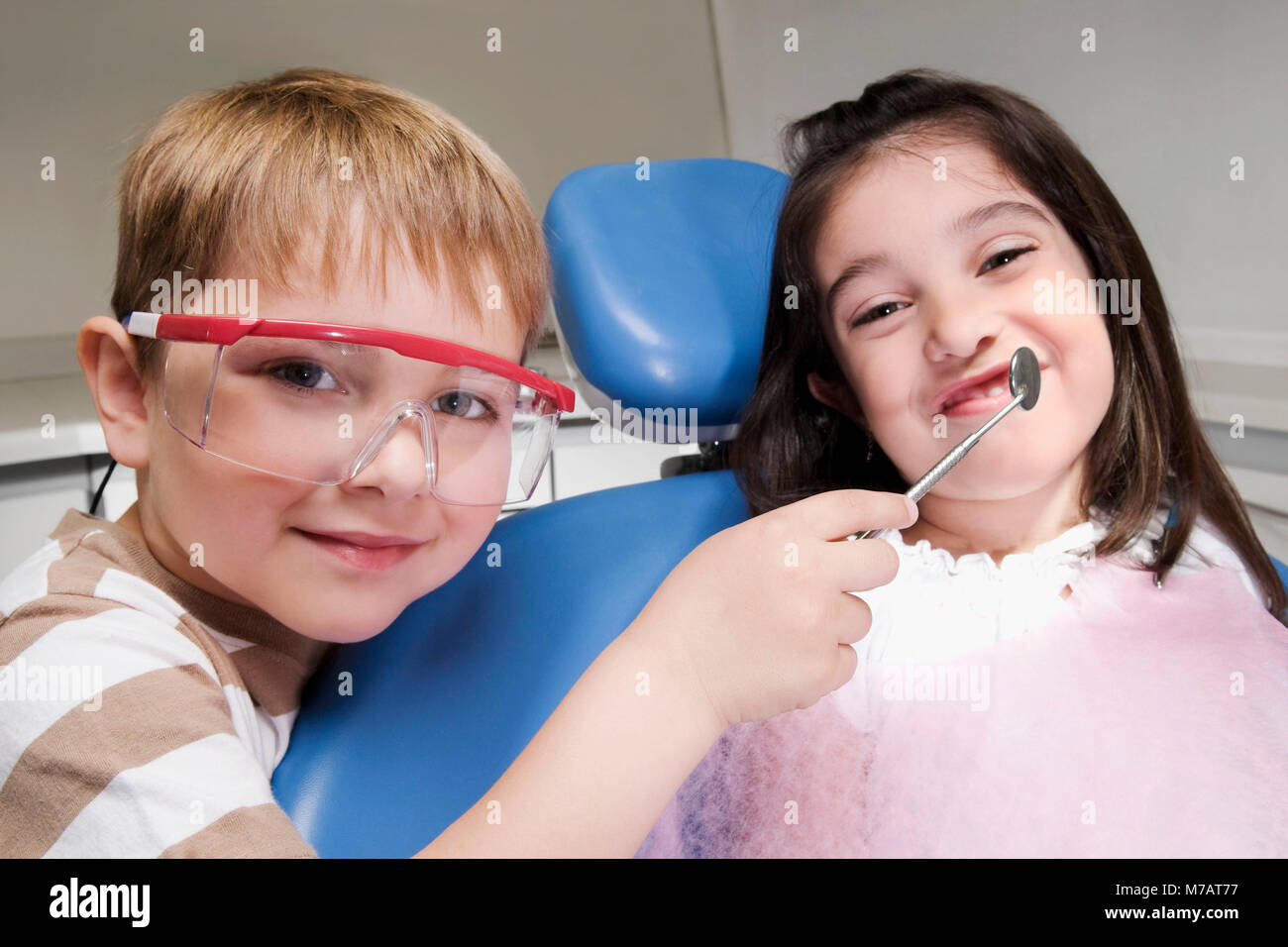 Boy imitating as a dentist and examining a girls teeth hires stock