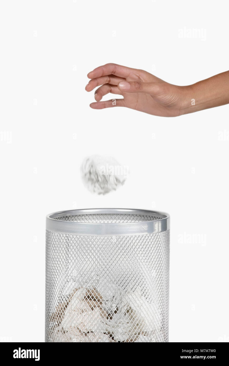 Close-up of a woman's hand throwing crumpled paper in a wastepaper basket Stock Photo