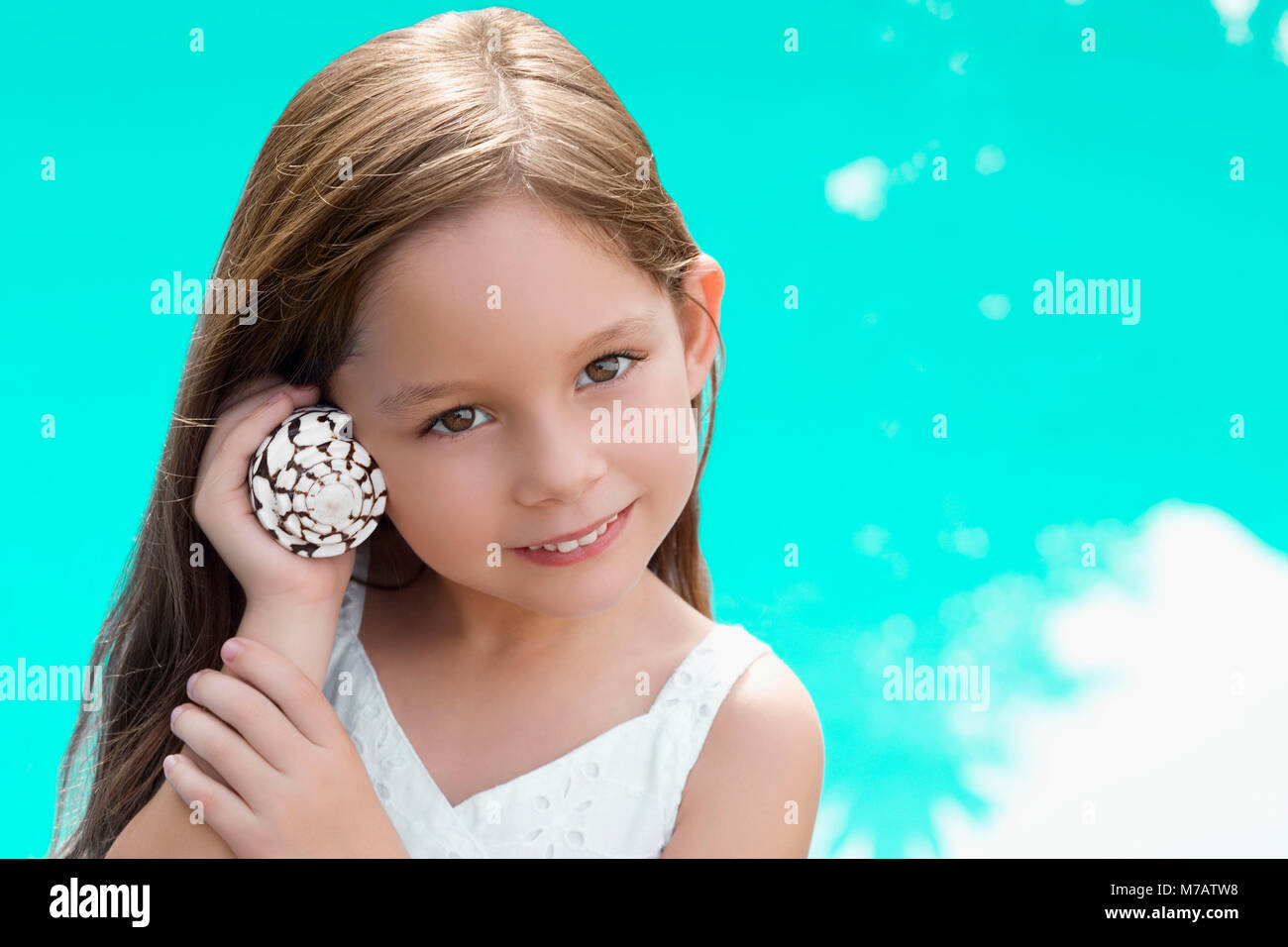Portrait of a girl holding a shell near her ear and smiling Stock Photo ...