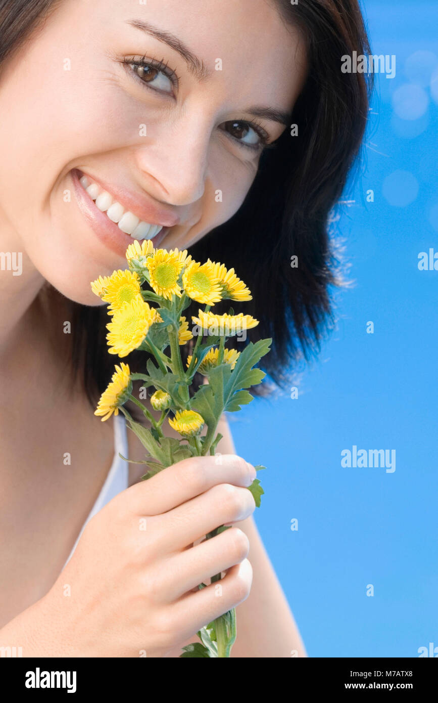 Portrait of a young woman smelling flowers and smiling Stock Photo - Alamy