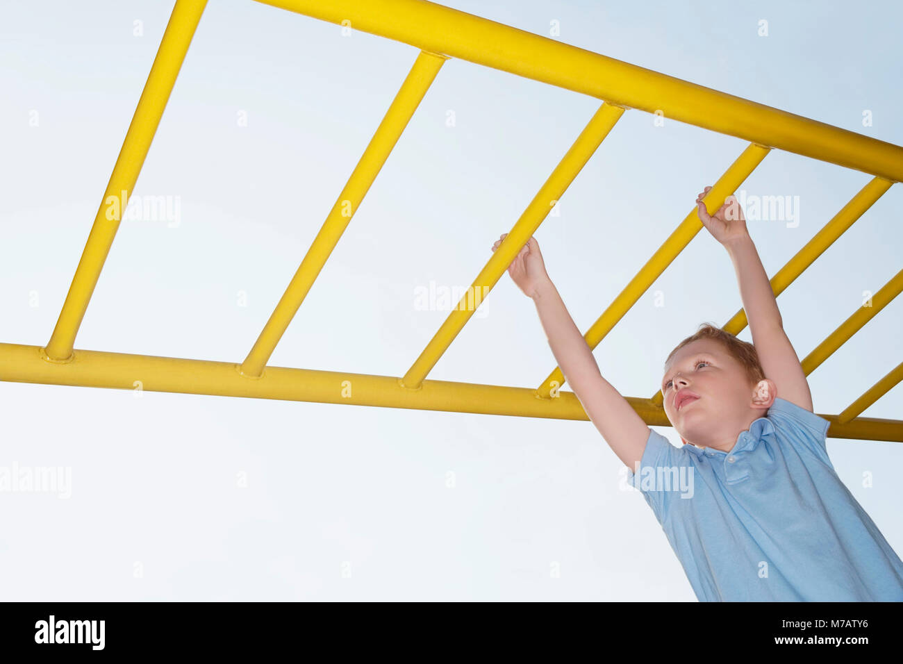 Low angle view of a boy hanging on monkey bars Stock Photo