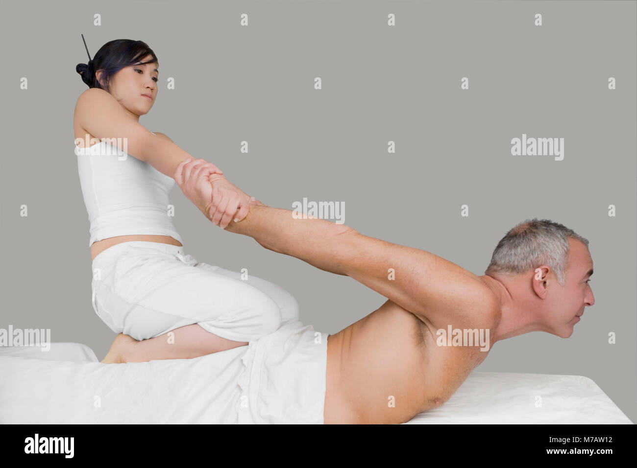 Side profile of a senior man receiving a back massage from a massage therapist Stock Photo