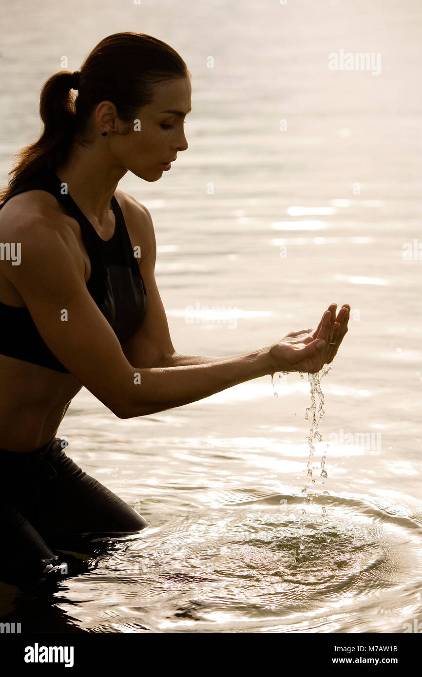Side profile of a young woman meditating in a lake Stock Photo
