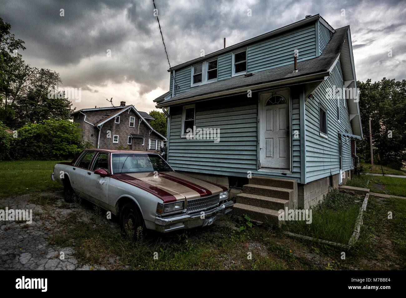 Abandoned car and home in abandoned neighborhood of