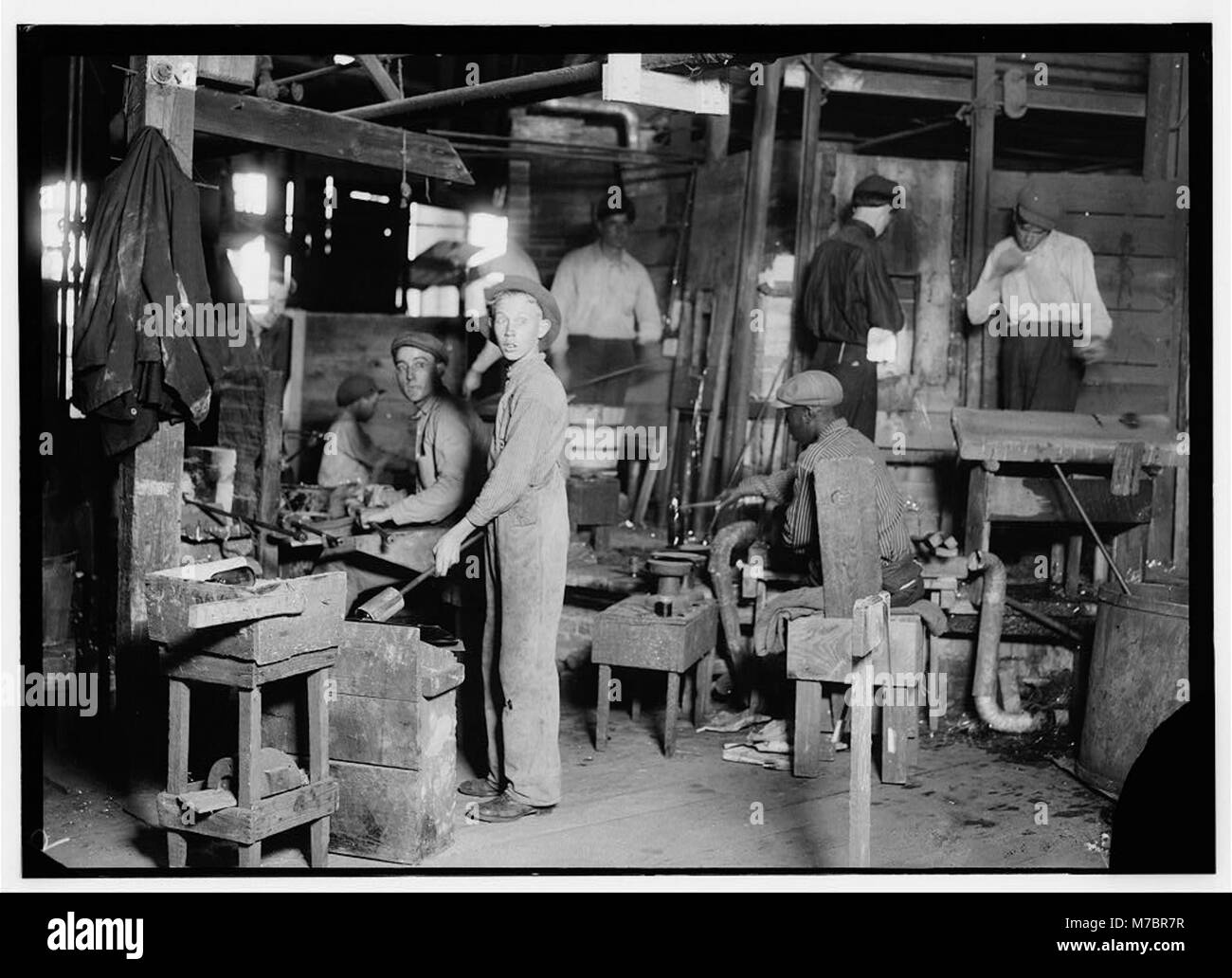 Cumberland Glass Works, Bridgeton, N.J. A young 'holding-mold boy' is seen, dimly, in middle distance to left of centre. Negroes, Greeks and Italians are being employed in many glass houses. LOC nclc.05437 Stock Photo