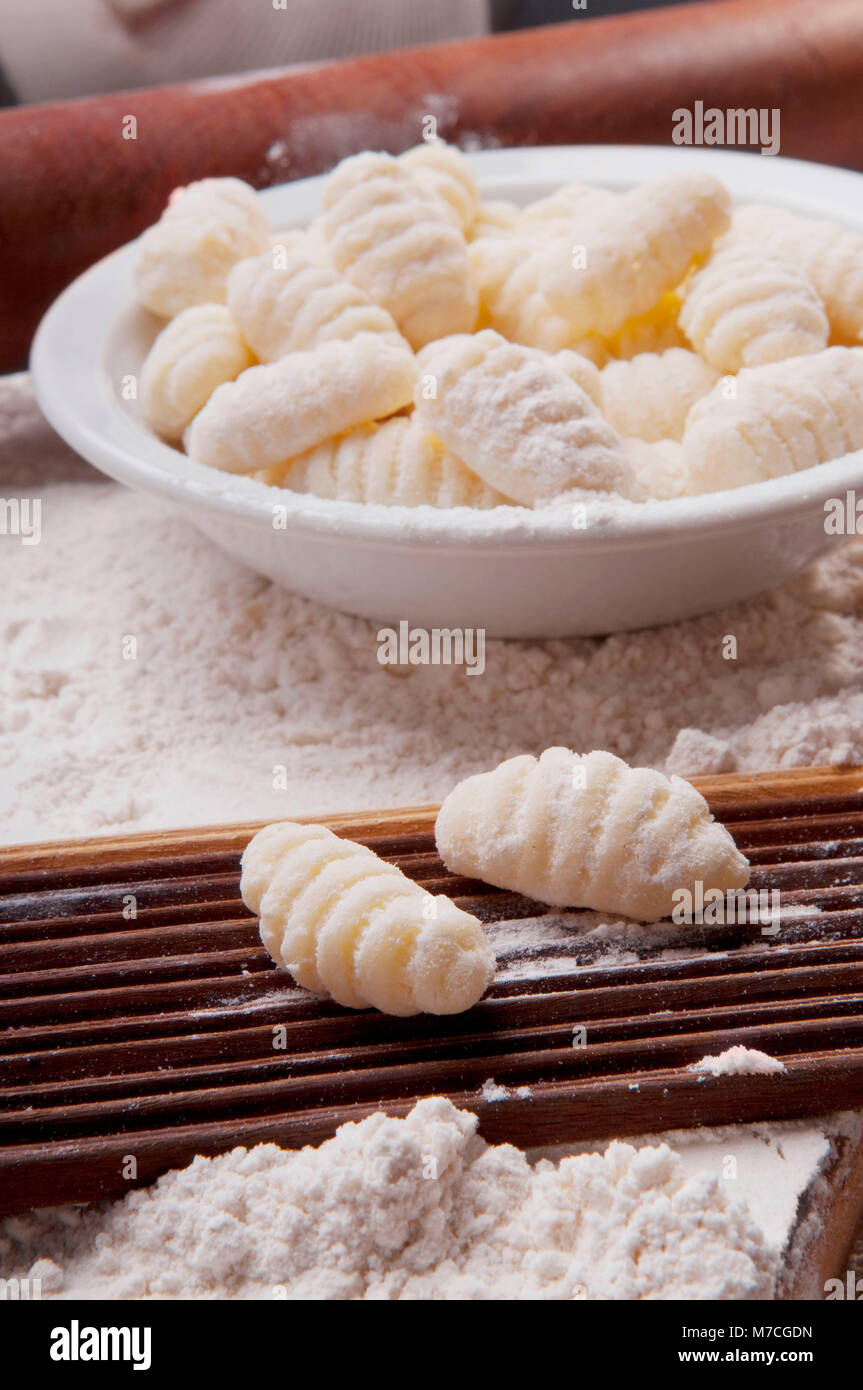 Bowl of homemade gnocchi with mould and a rolling pin Stock Photo