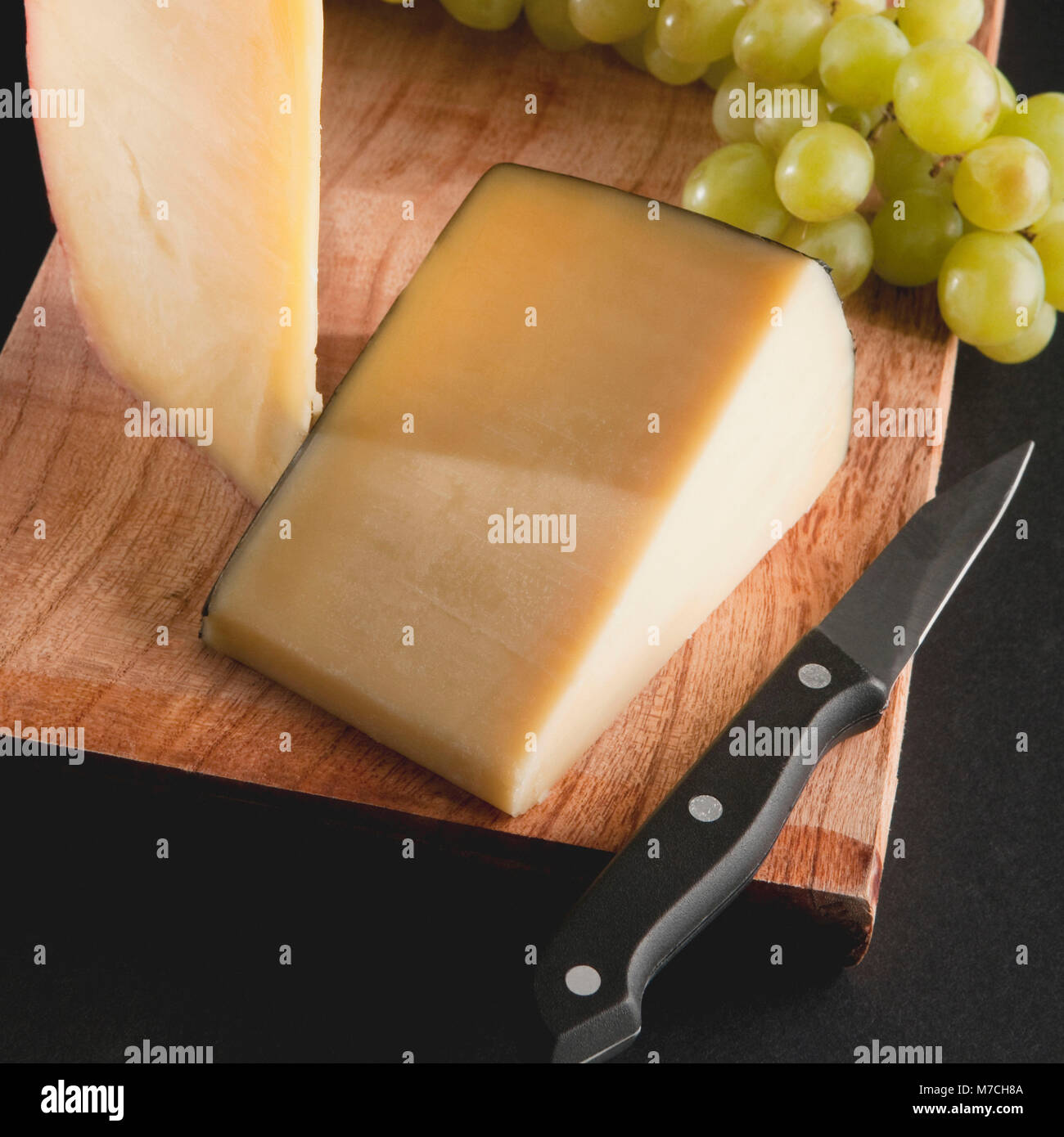 Close-up of cheeses with green grapes on a cutting board Stock Photo