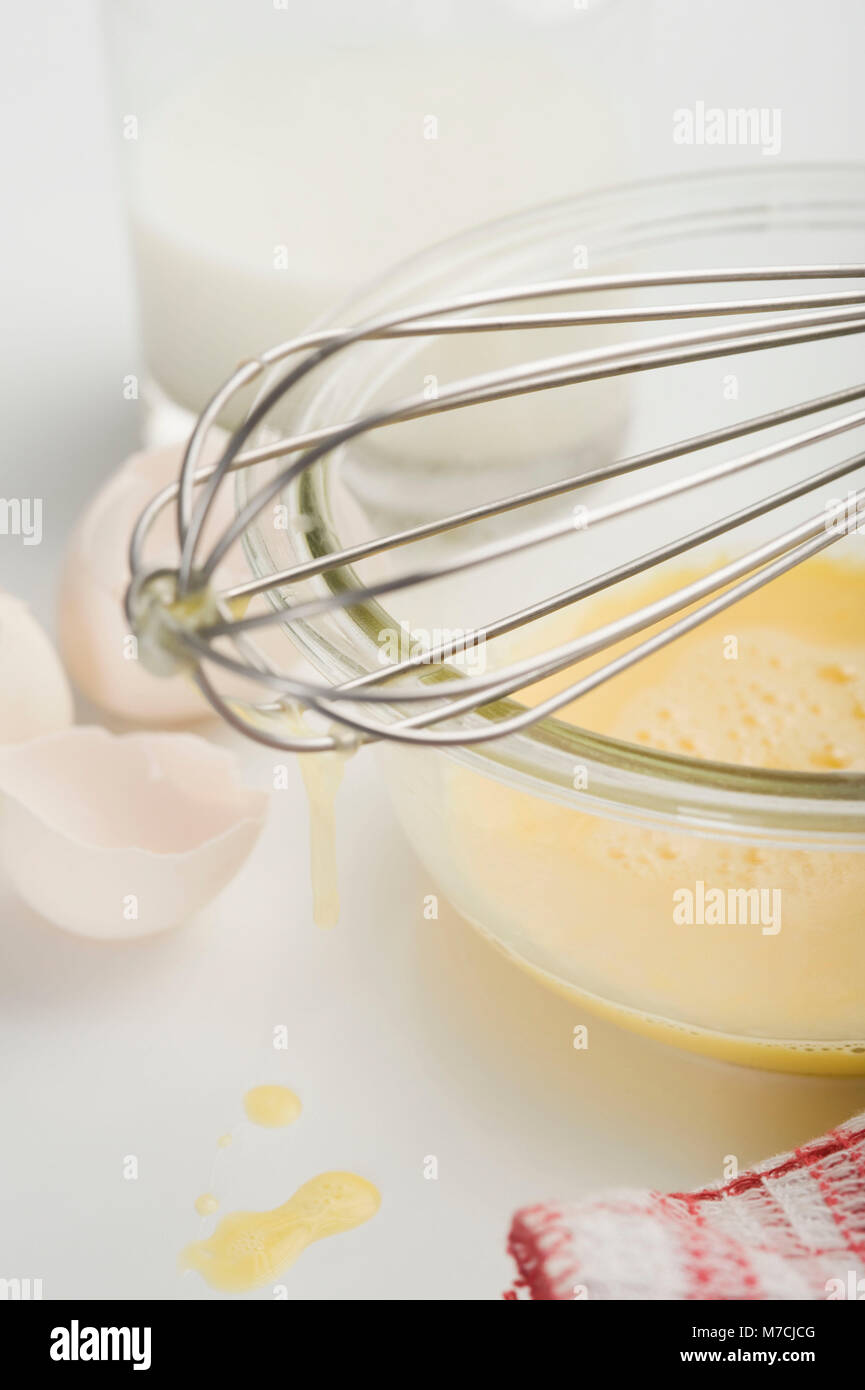 Egg yolk and milk with wire whisk in bowl hires stock photography and