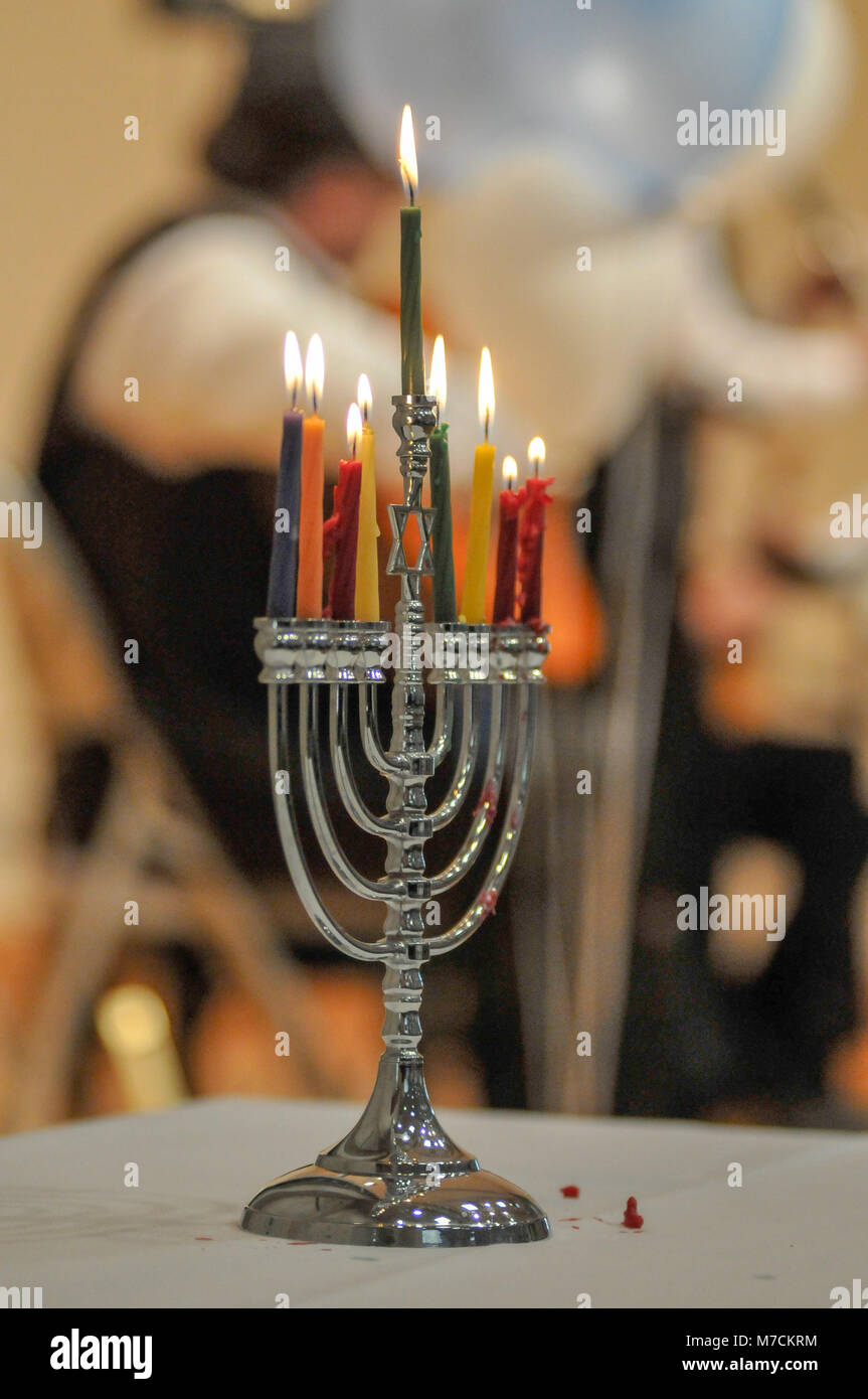 A Menorah  with eight candles burns at a Jewish holiday concert.  Candles in foreground and Jewish band blurred out in the background. Stock Photo