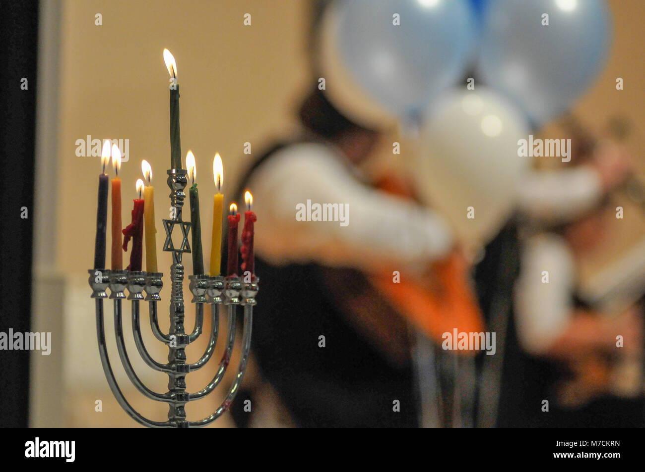 A Menorah  with eight candles burns at a Jewish holiday concert.  Candles in foreground and Jewish band blurred out in the background. Stock Photo