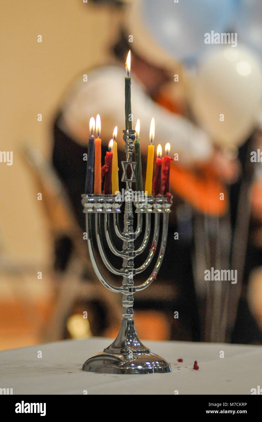 A Menorah  with eight candles burns at a Jewish holiday concert.  Candles in foreground and Jewish band blurred out in the background. Stock Photo