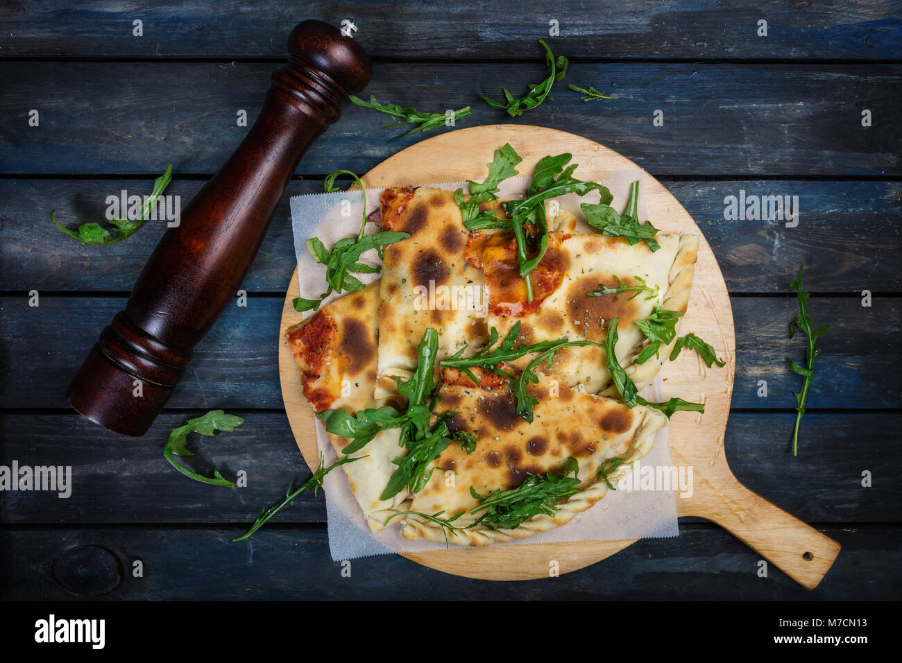 Calzone - Stuffed Pizza with ham, mushrooms, arugula and cheese. Stock Photo