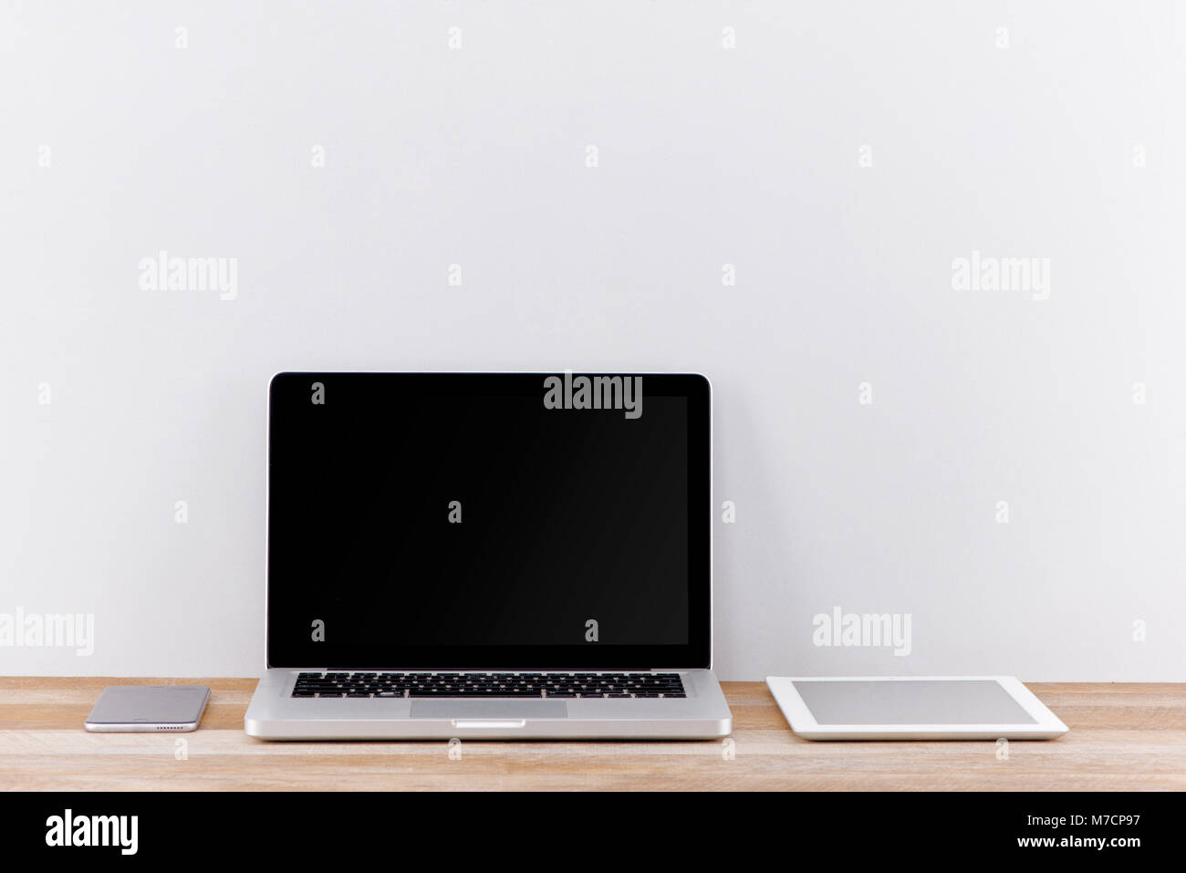 Creative web design agency presentation on multiple devices. Computer display, laptop, tablet, smart phone on white wooden desk. Brick white wall in b Stock Photo