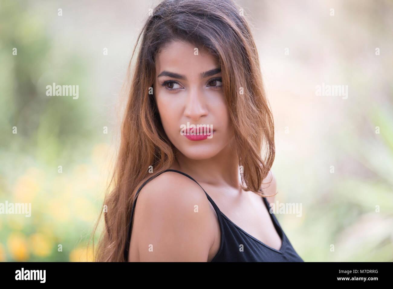 Close up of a beautiful young woman looking over shoulder outdoors Stock Photo