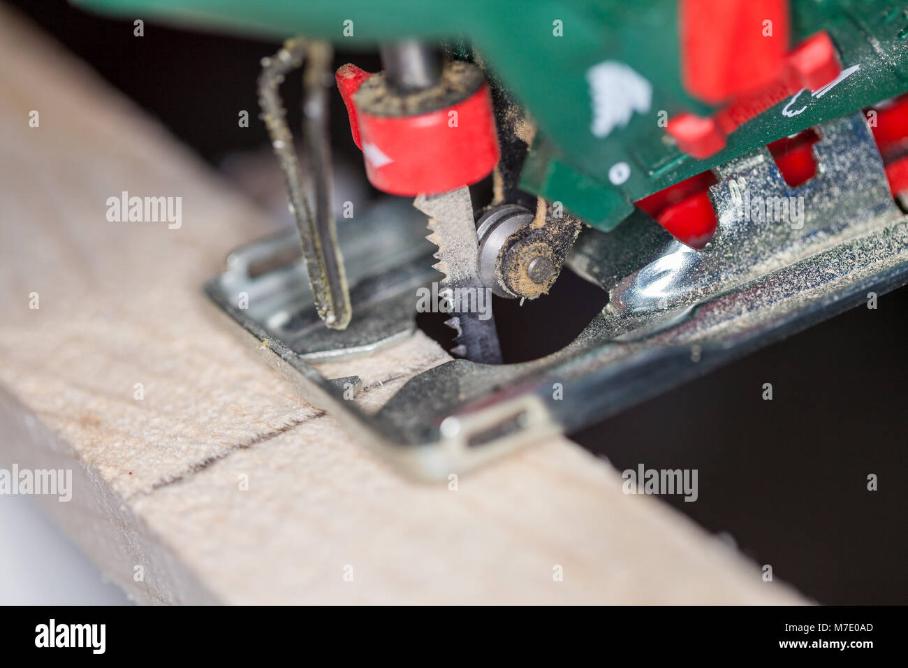 a green jigsaw saws a bright plank Stock Photo