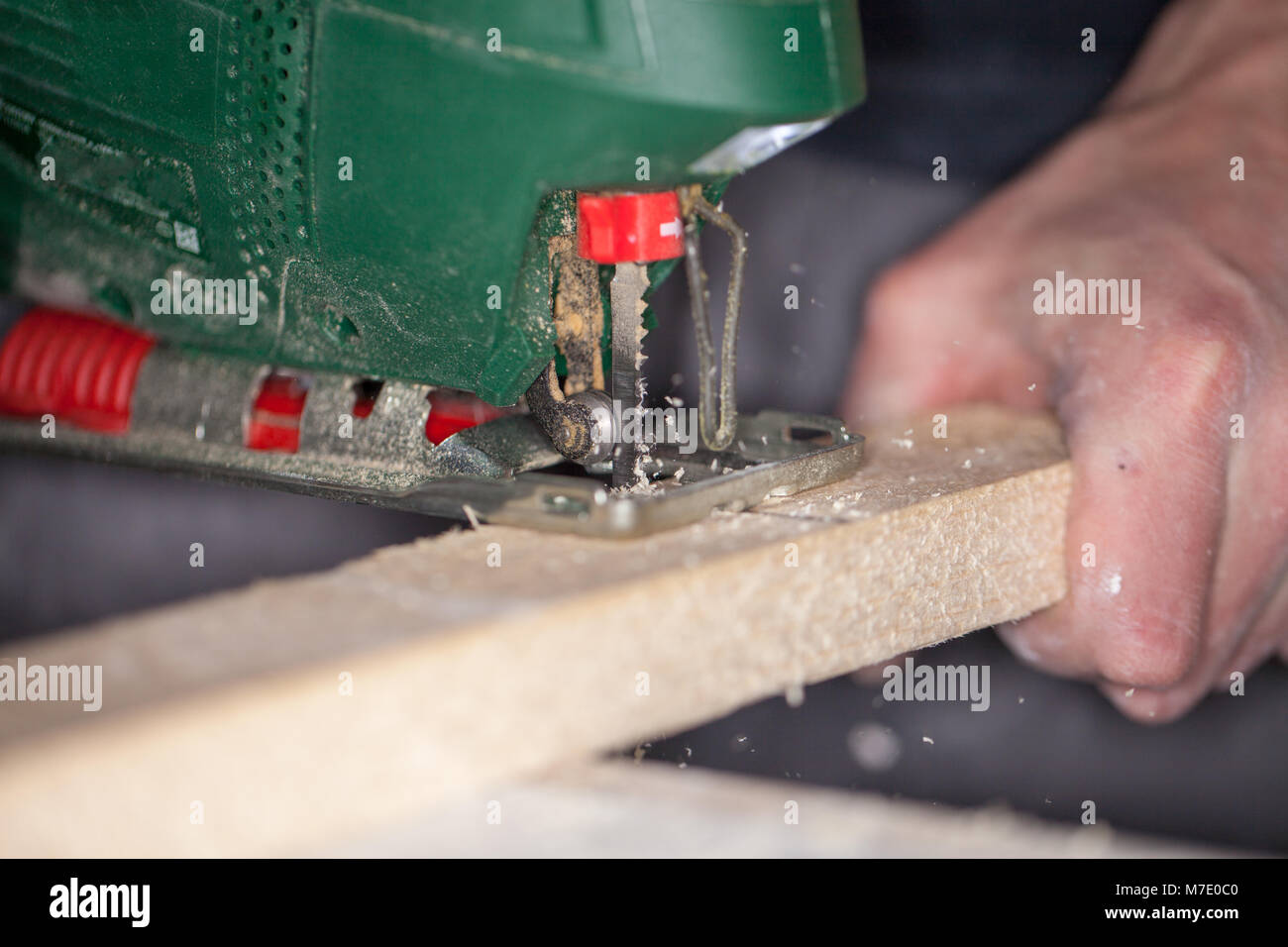 a green jigsaw saws a bright plank Stock Photo