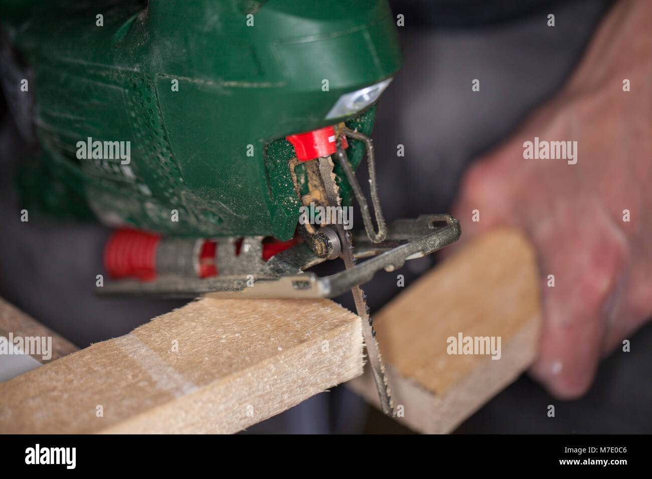 a green jigsaw saws a bright plank Stock Photo