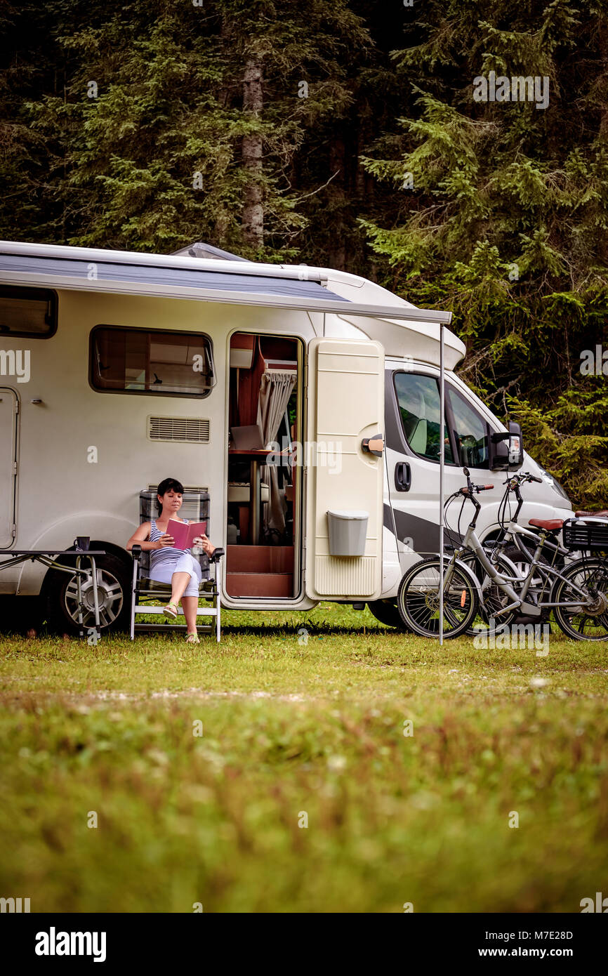 Woman relaxes and reads a book near the camping . Caravan car Vacation. Family vacation travel, holiday trip in motorhome RV. Stock Photo