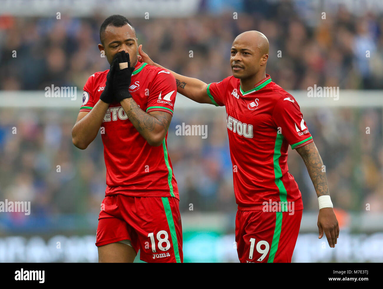 Swansea City's Jordan Ayew is consoled by brother and team matesSwansea  City's Andre Ayew after being shown the red card during the Premier League  match at the John Smith's Stadium, Huddersfield Stock