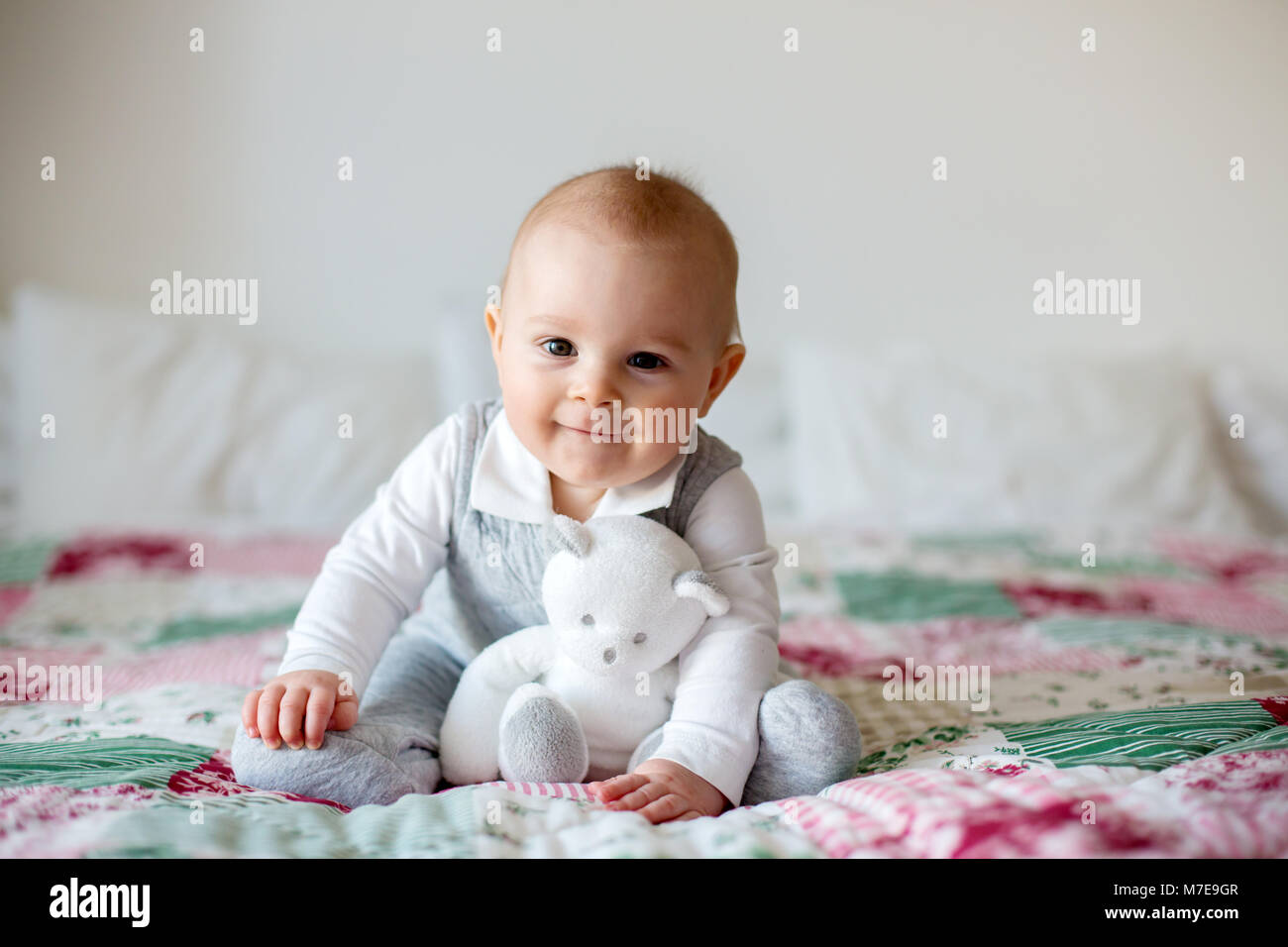 Portrait of a cute smiling infant baby boy playing with teddy bear toy ...