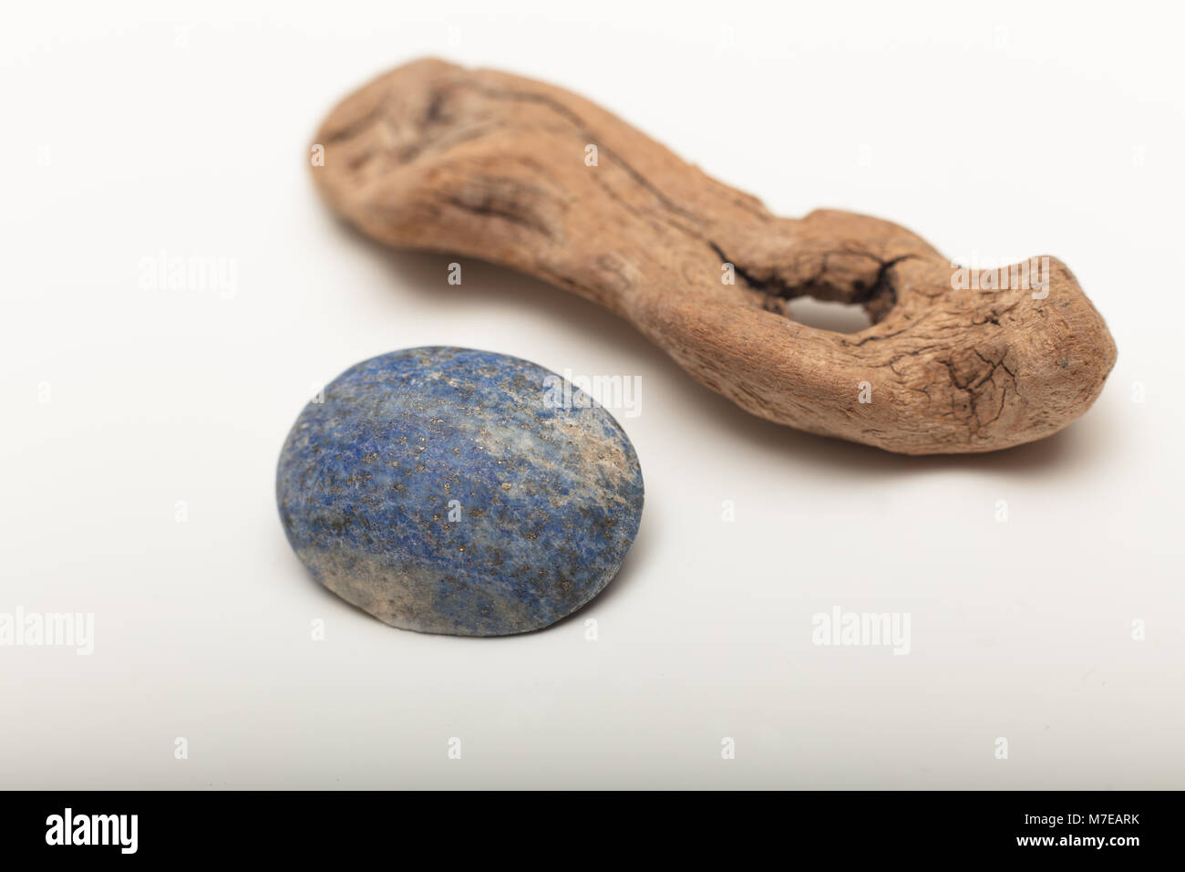 Lapis lazuli  is a deep blue metamorphic rock used as a semi-precious stone on a white background with old wood Stock Photo