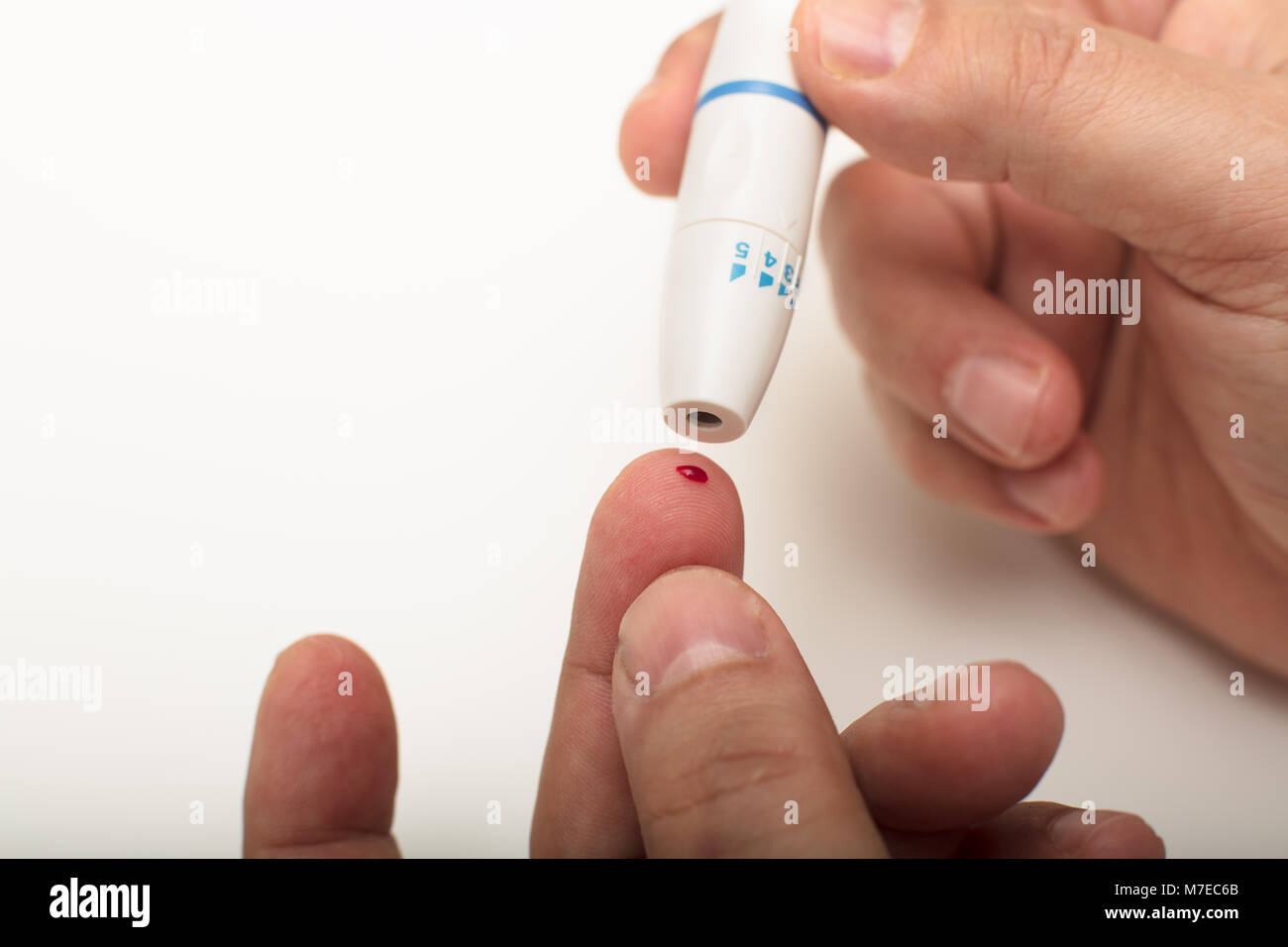 Man pricking his finger with a portable lancet to draw a blood sample