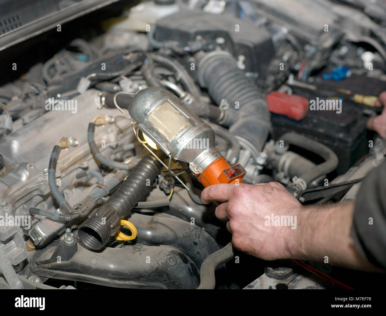 Man hand with portable torch inspecting a car engine, indoor closeup ...