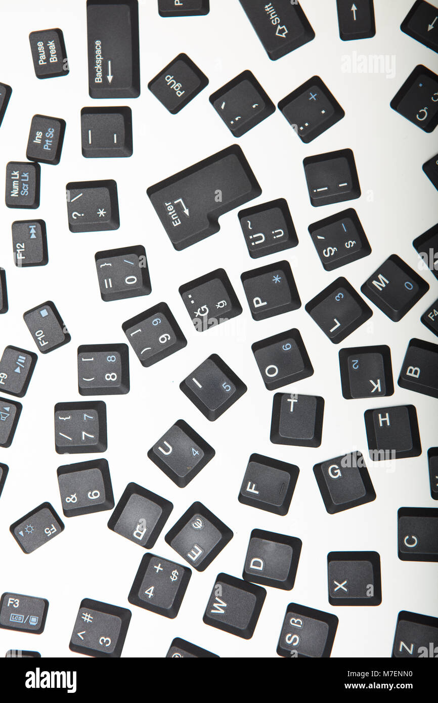 Loose alphanumeric covers for the keys on a laptop computer keyboard scattered randomly on a white surface viewed high angle with foreground copy spac Stock Photo