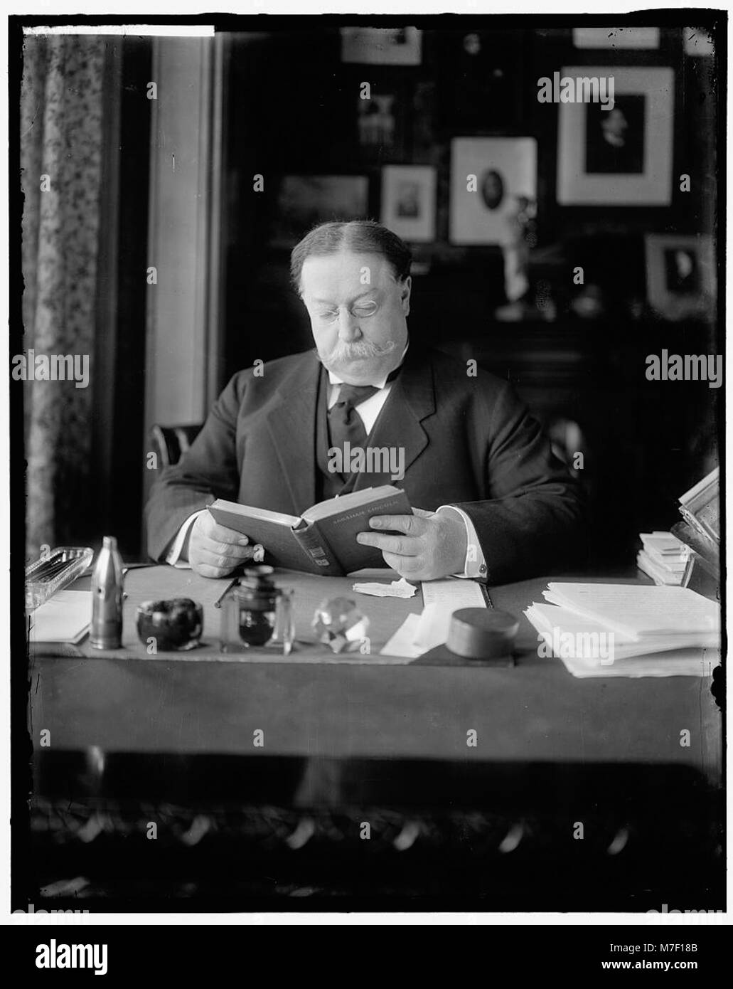 A formal portrait of William H. Taft, U.S. Secretary of War, reading at ...