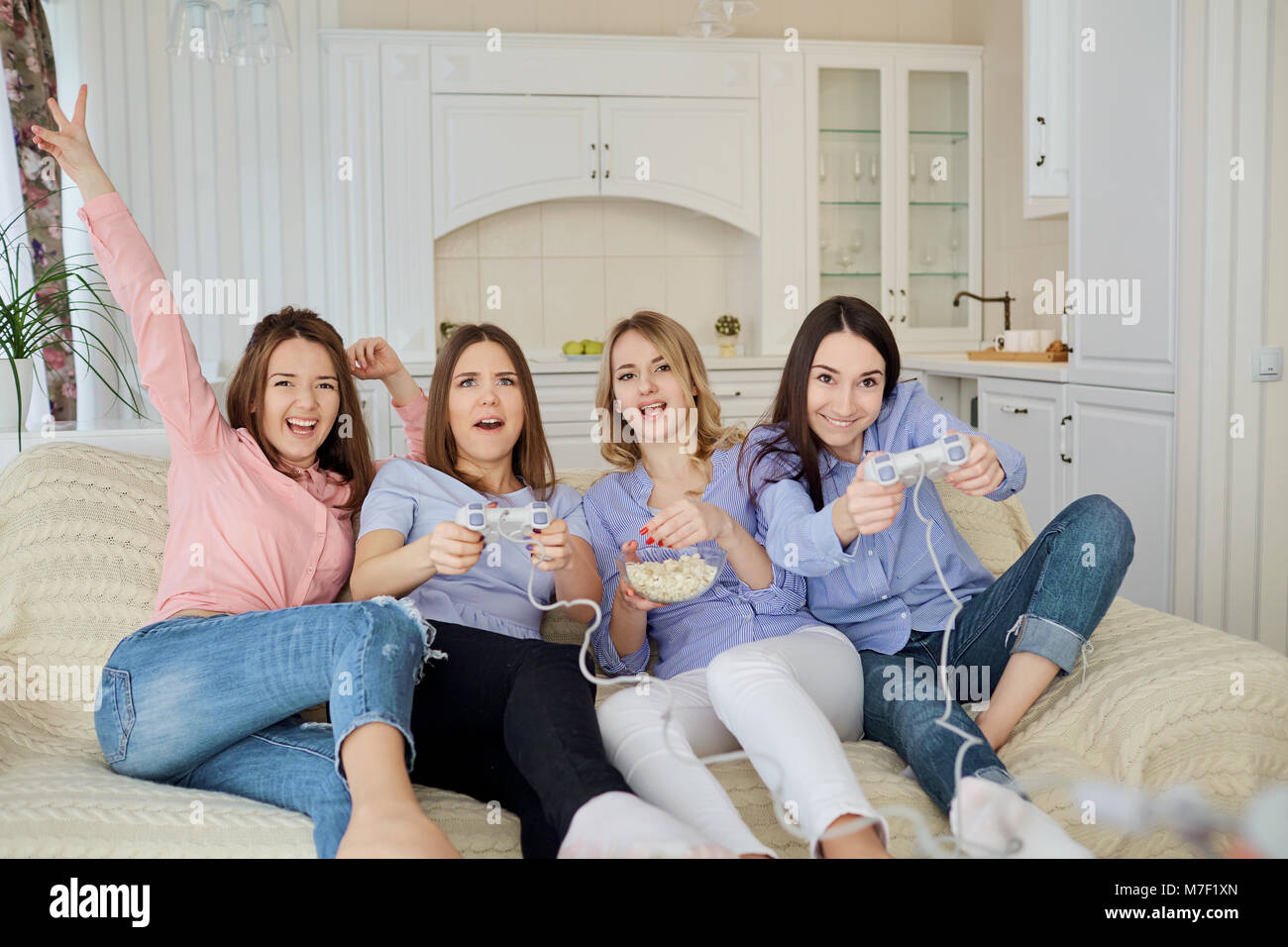 Girlfriends are playing video games sitting on the couch. Stock Photo