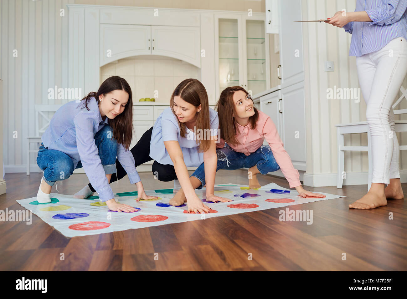A group of friends play in games on the floor indoors. Stock Photo