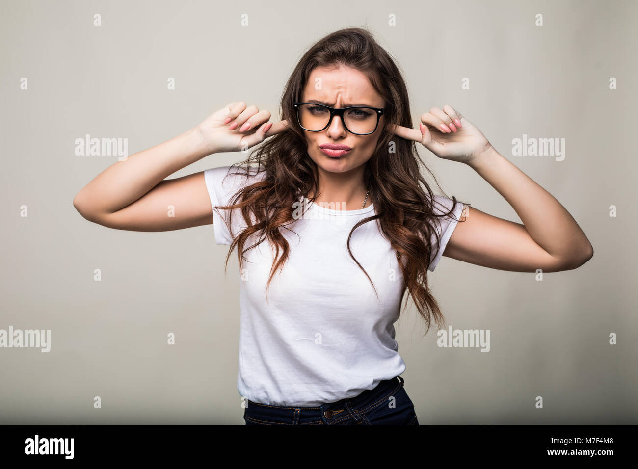 Close up portrait of angry stressed out young woman plugging ears with ...