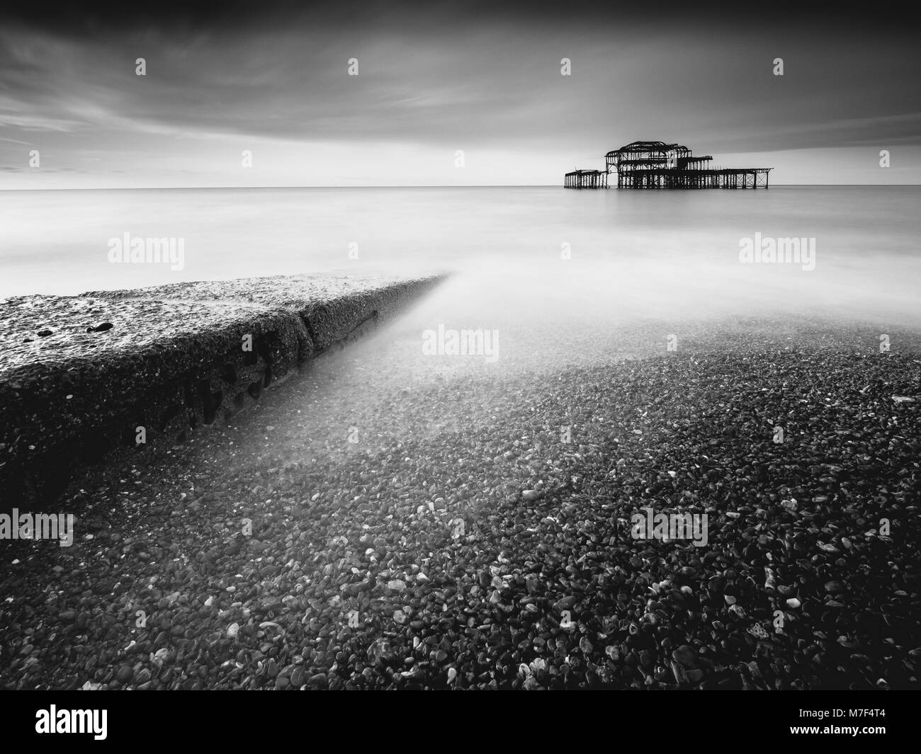 A stone jetty points towards the old ruined West Pier. Stock Photo