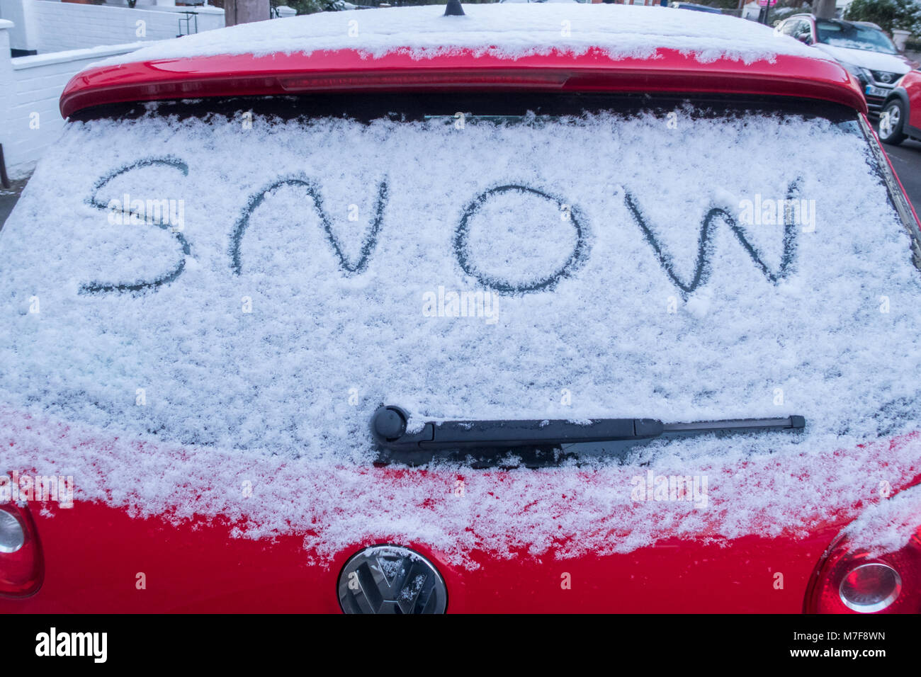 The word snow written on the rear window of a snow covered car Stock