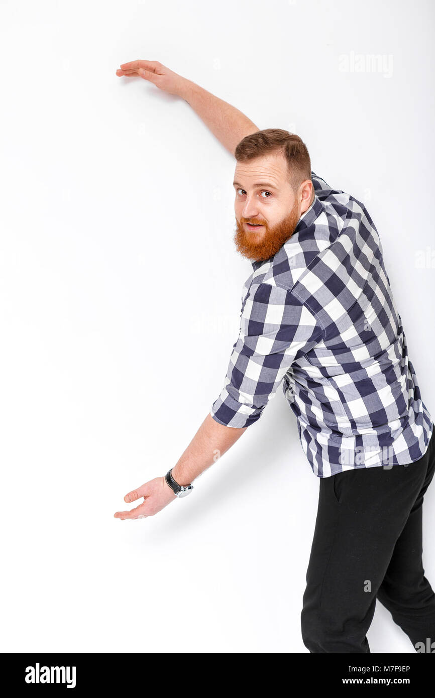 handsome man with beard pointing copy space. young man in plaid shirt showing large size of something Stock Photo