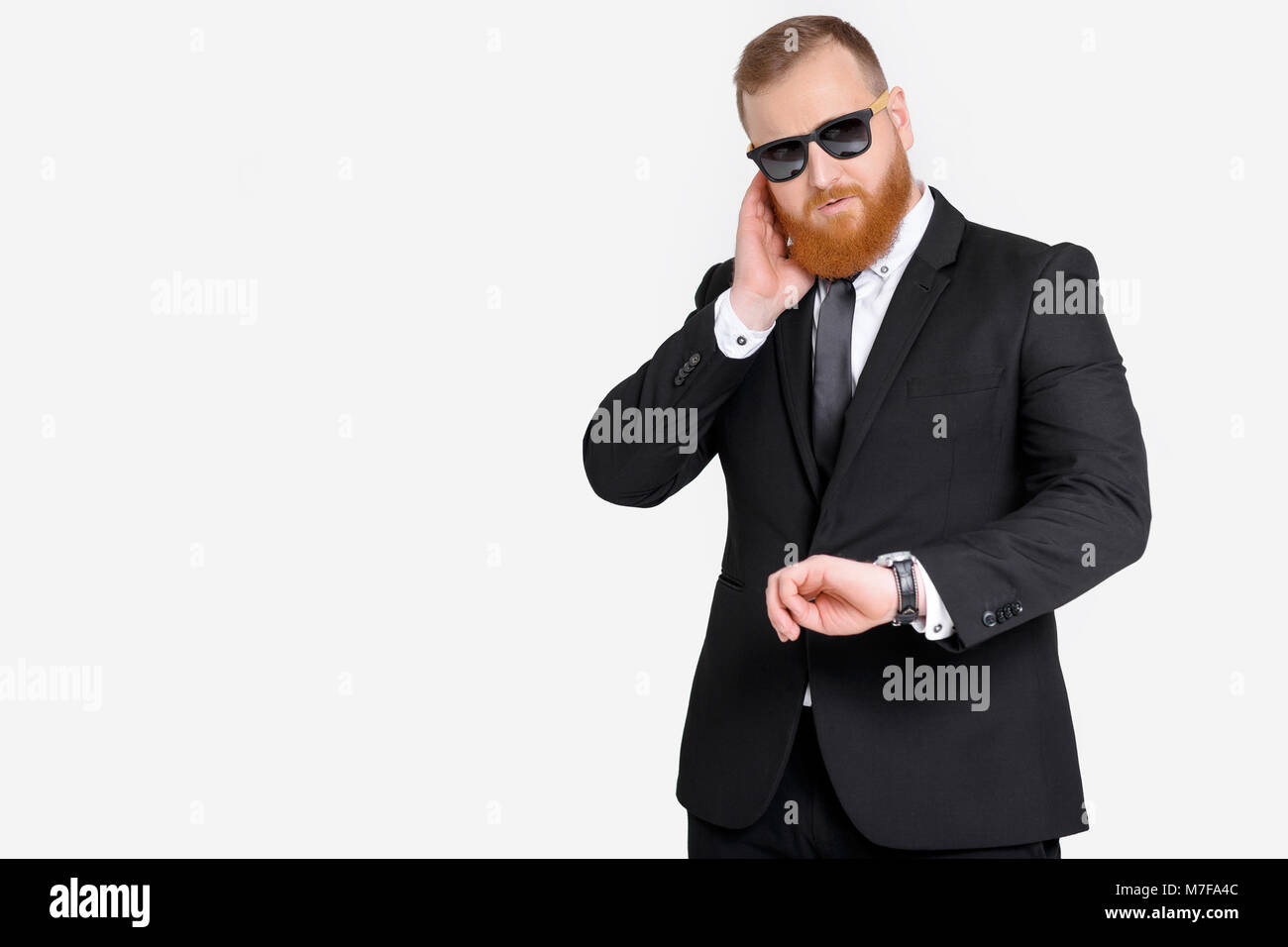 security guard in black suit looks at watch Stock Photo - Alamy